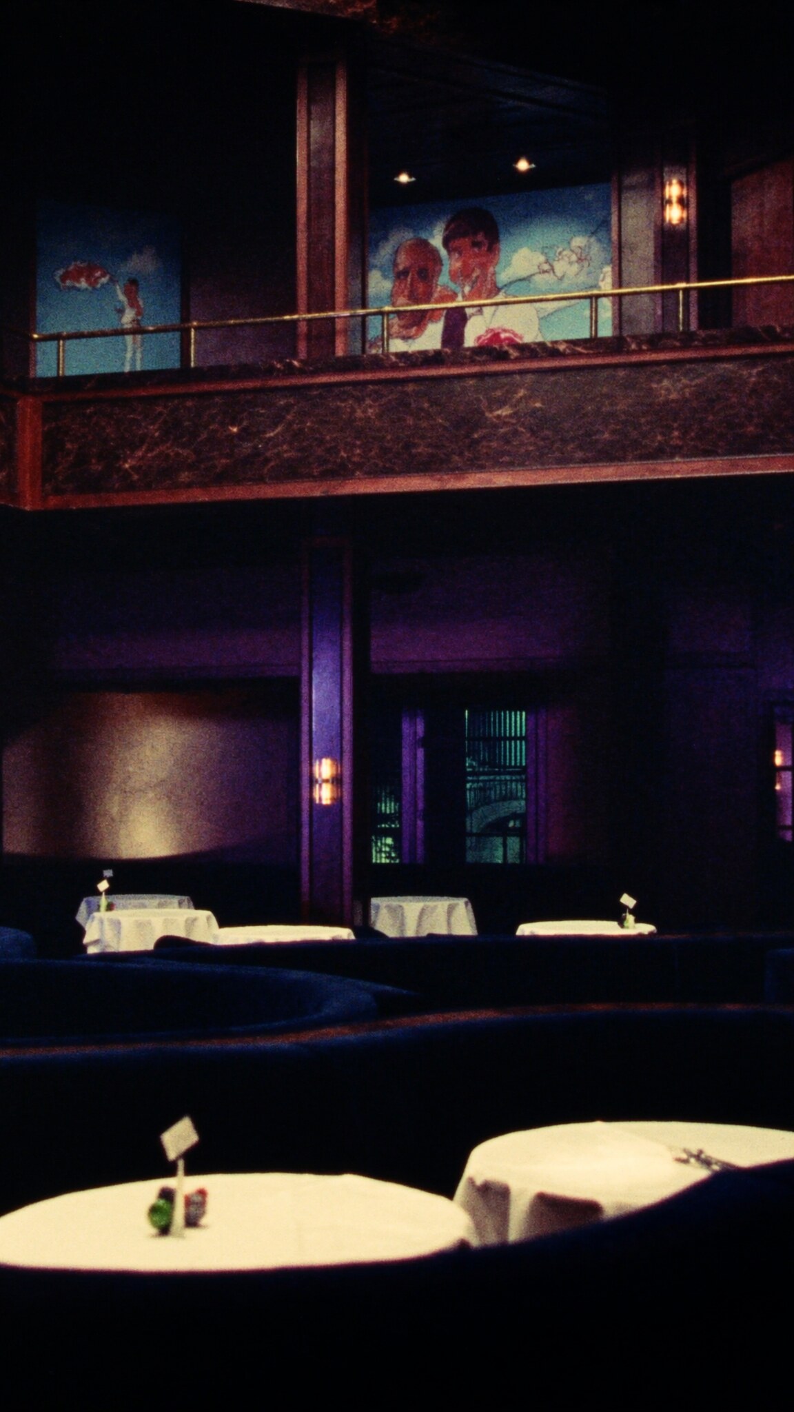 The dining room in a tall portrait frame, the mezzanine rail above and banquettes below