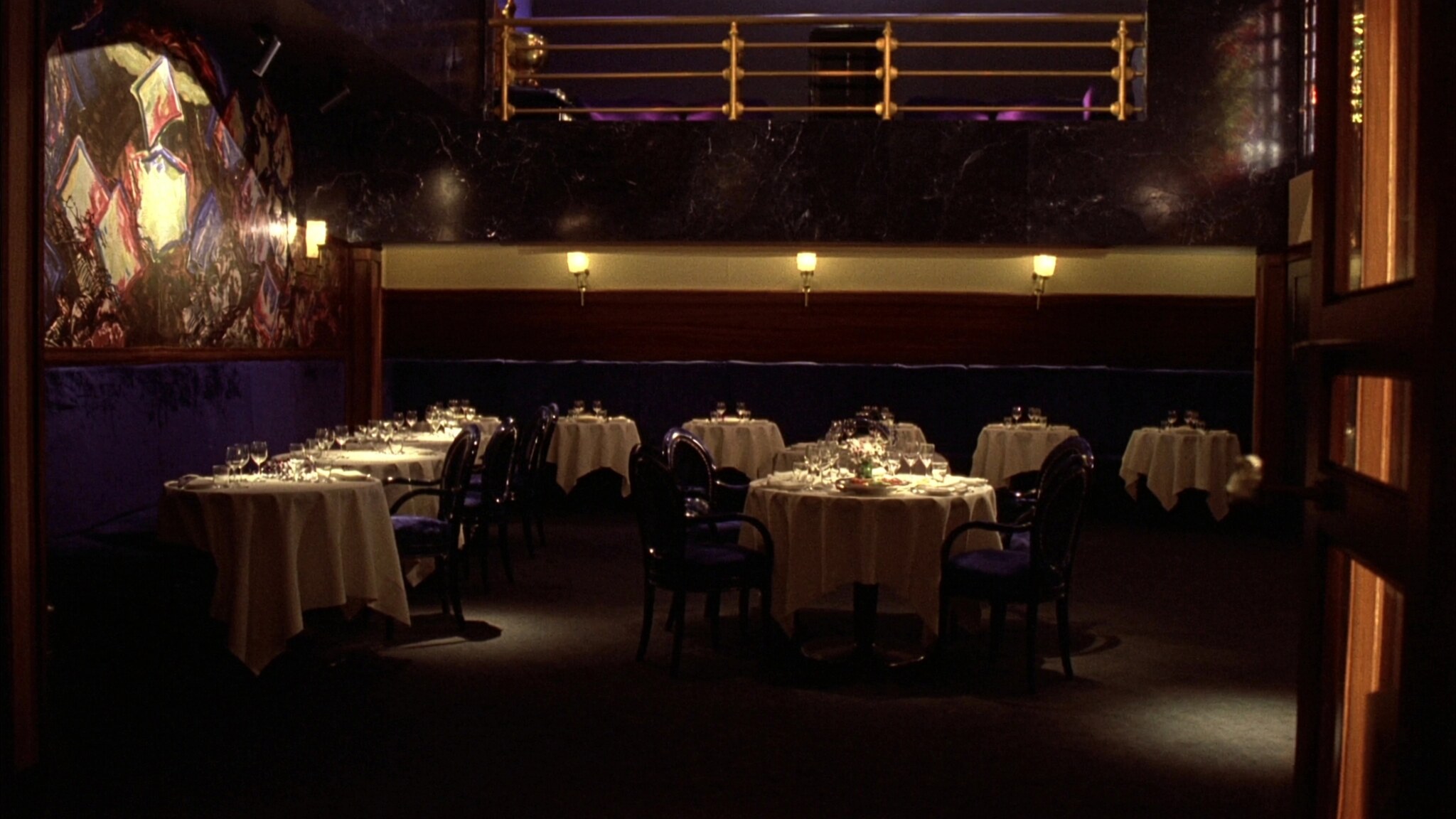 A dining room set for service under a brass mezzanine rail