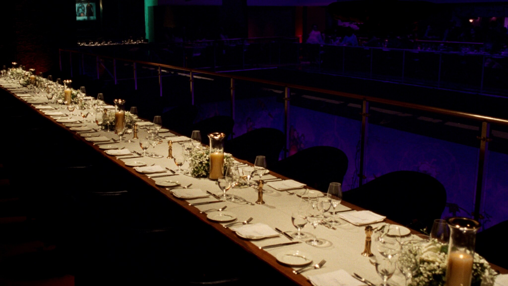 A long private dining table set with cream linen and brass candlesticks