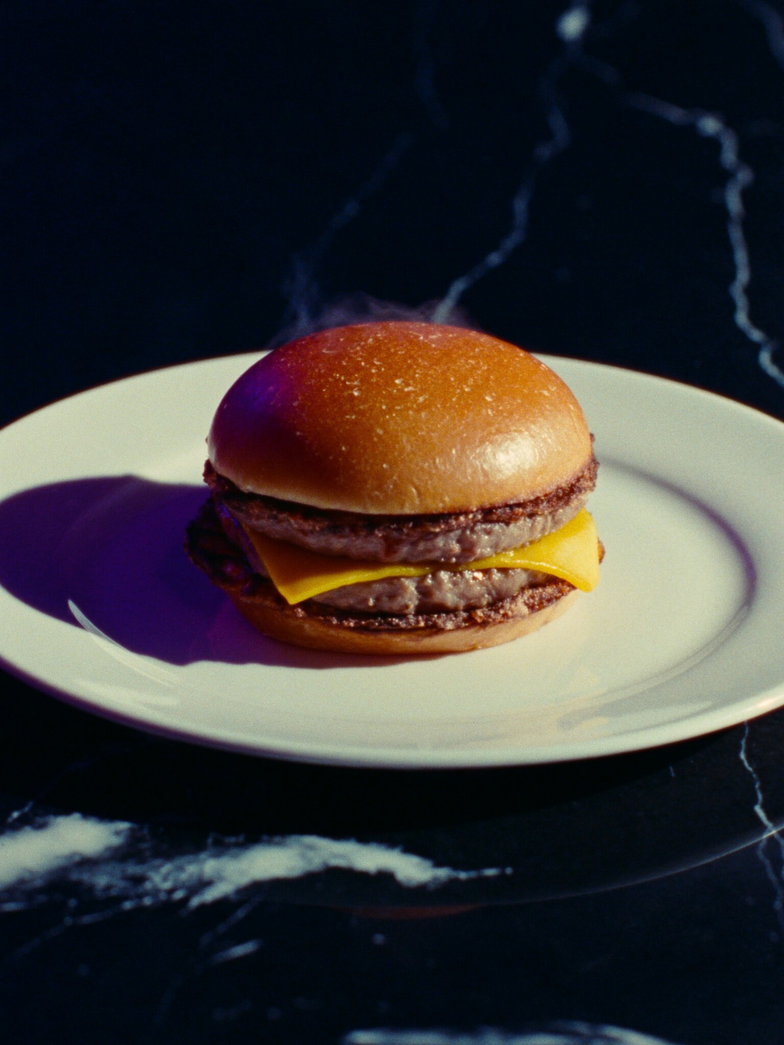 A wagyu double smash burger on a cream plate under hard side light