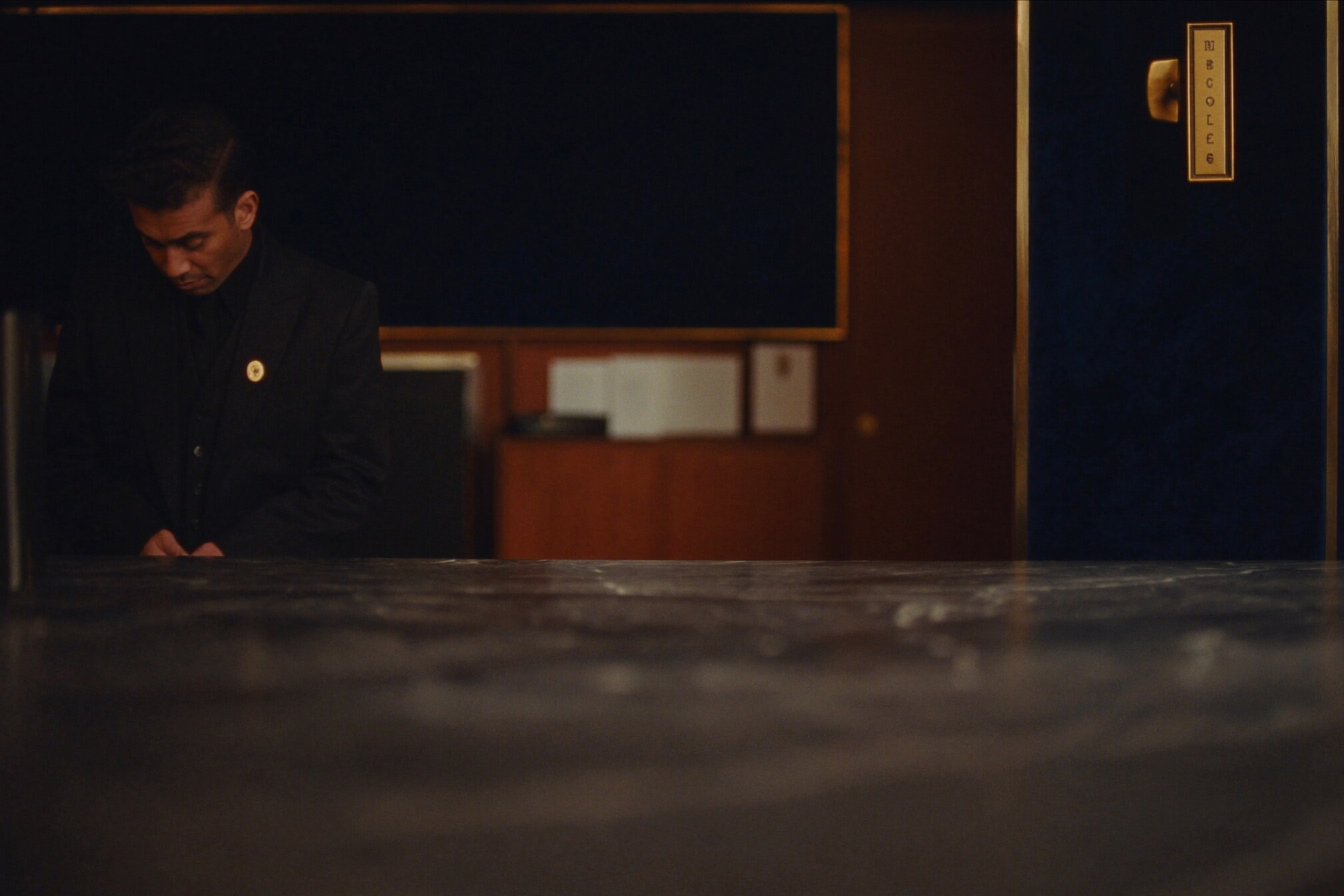 A captain in a black uniform with a brass pin at the marble bar before service